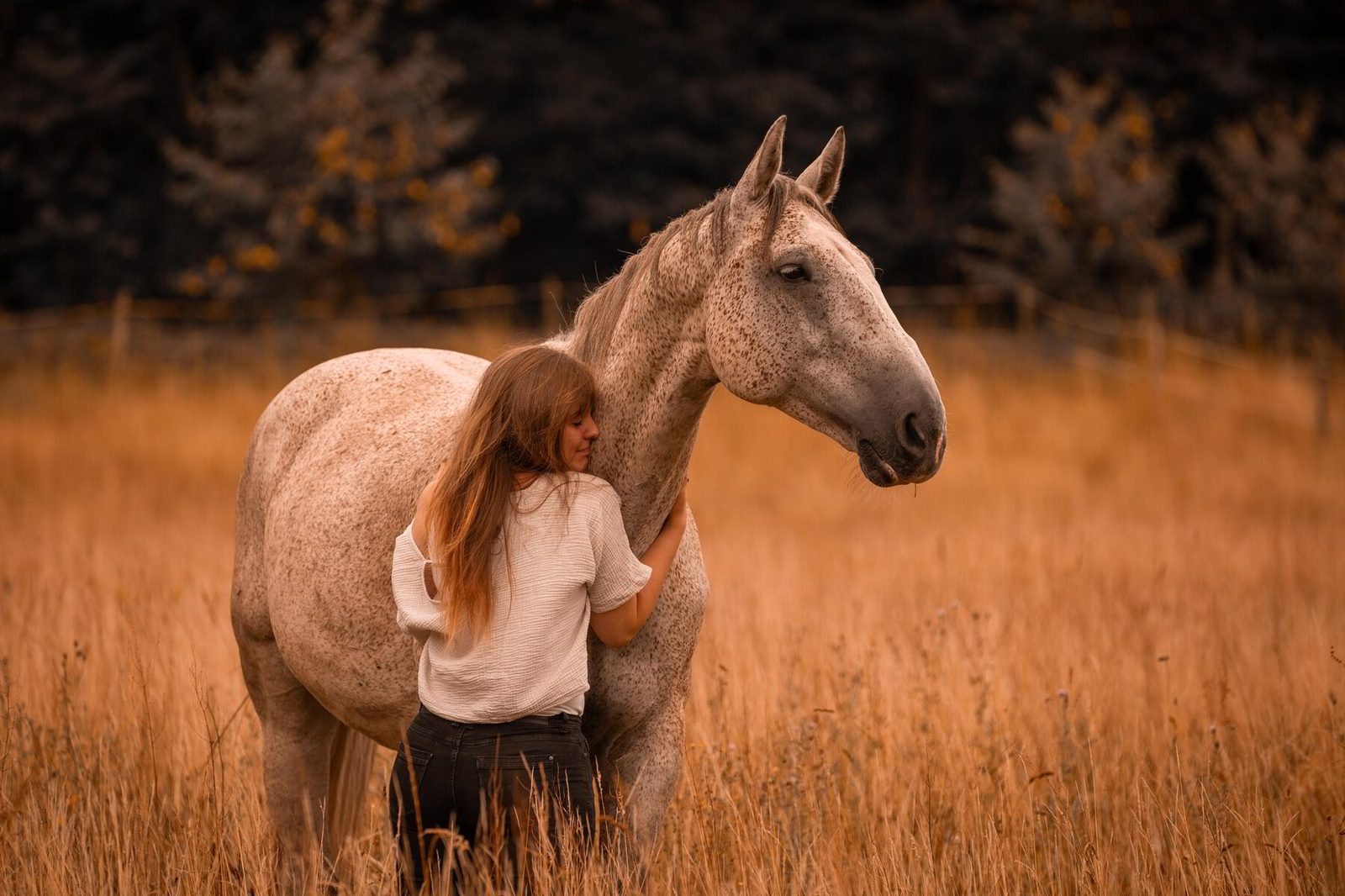 Ramona umarmt ihr Pferd im hohen Gras